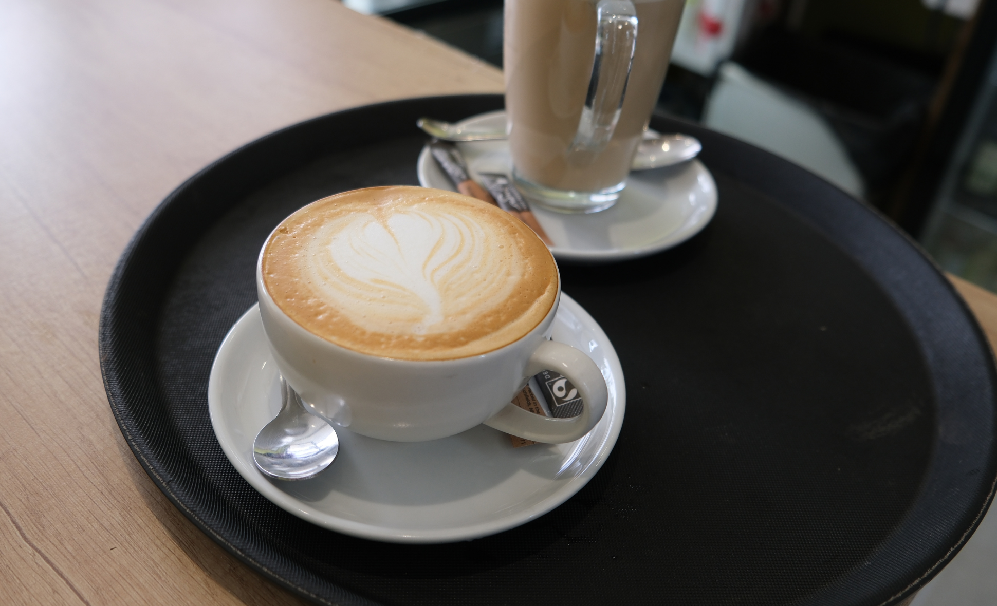 A coffee with a love heart on top, on a black tray