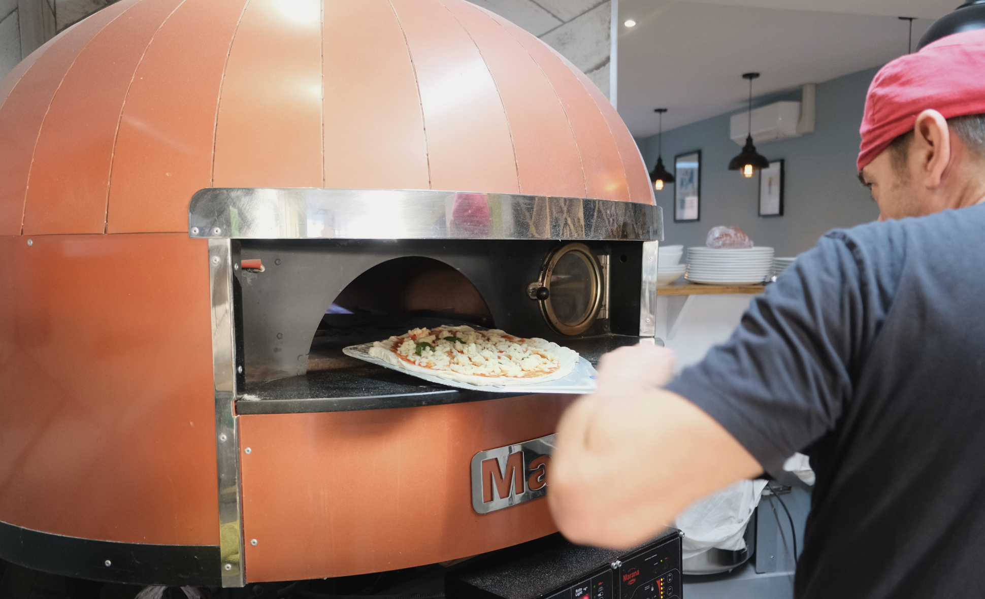 A chef putting a pizza into a pizza oven